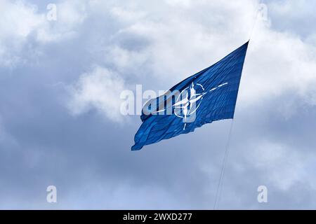 Bandiera NATO sul cielo nuvoloso. Volare nel cielo Foto Stock