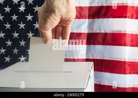 Mano che mette il suo voto nelle urne contro la bandiera nazionale degli Stati Uniti Foto Stock