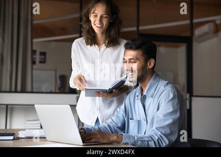 Allegri colleghi di lavoro diversi che parlano e ridono del notebook Foto Stock