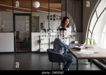Due giovani e felici colleghi multietnici godono della cooperazione e del lavoro di squadra Foto Stock