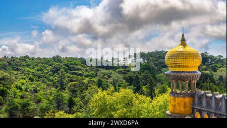 Ampia vista esterna della torre di guardia con cupola decorata con piastrelle gialle del Palácio da pena, sotto un cielo azzurro nuvoloso e soleggiato, con il frondoso Sie Foto Stock