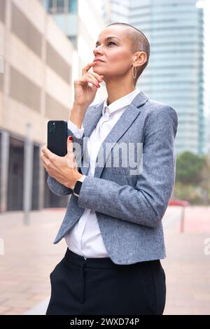 Donna d'affari caucasica premurosa che utilizza un'app sul suo smartphone all'aperto. Foto Stock