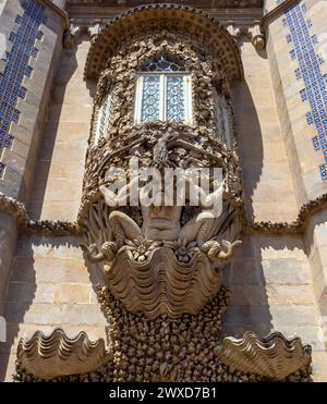 Statua o scultura di Tritone, dio greco del mare, su una conchiglia con sculture decorative in pietra che custodisce l'ingresso al Palazzo da pena. Foto Stock