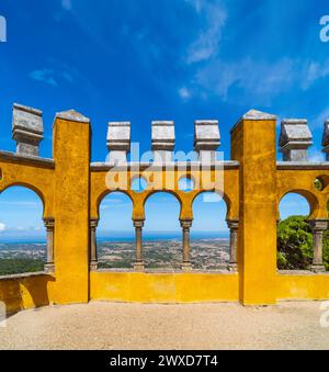 Archi moreschi del cortile ad arco con le pareti dipinte di giallo del Palácio da pena, uno dei castelli più belli d'Europa, sotto un chiaro edificio Foto Stock