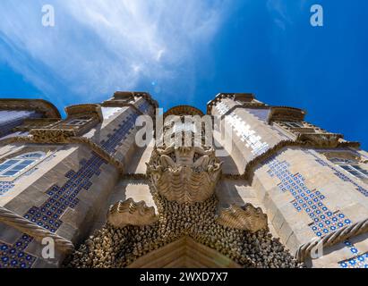 Vista ad angolo basso della Statua di Tritone su una conchiglia con sculture decorative in pietra che custodisce l'ingresso al Palazzo pena, con le torri decorate Foto Stock