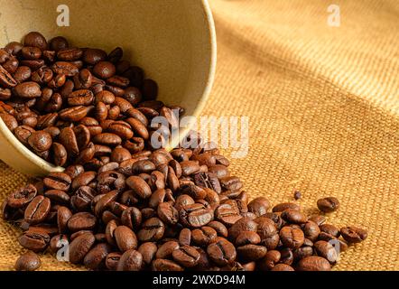 Chicchi di caffè in una ciotola su tessuto burlap Foto Stock