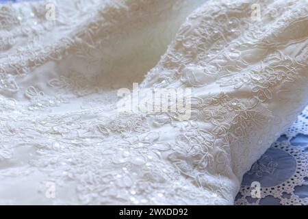 primo piano di un elaborato motivo in pizzo su un abito da sposa, che mette in risalto la raffinata artigianalità e l'eleganza dell'abbigliamento da sposa Foto Stock