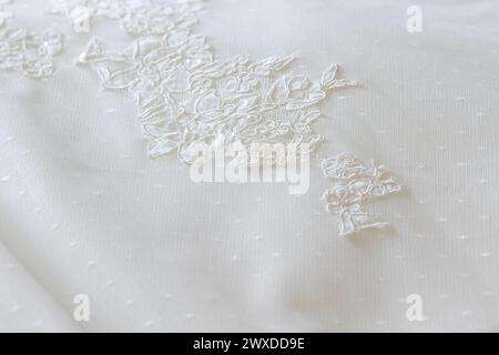 lo squisito ricamo su un tessuto da sposa cattura gli intricati dettagli in pizzo tipici di un abito da sposa Foto Stock