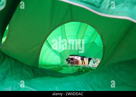 Una prospettiva interna unica di un pallone ad aria calda, che mostra il design complesso mentre si gonfia, con persone che lavorano in background Foto Stock