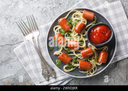 Buon cibo per bambini per la festa di Halloween, spaghetti con salsicce e ketchup da vicino in un piatto sul tavolo. Vista dall'alto orizzontale Foto Stock