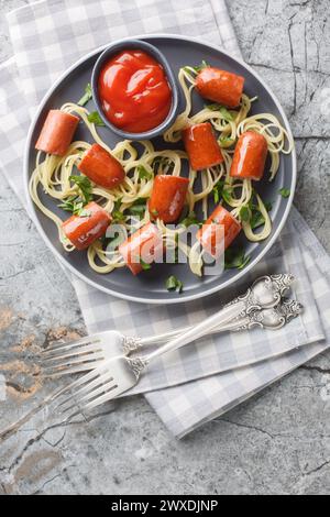 Piatto di spaghetti di Halloween con salsicce e ketchup da vicino in un piatto sul tavolo. Vista dall'alto verticale Foto Stock