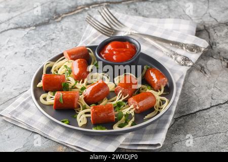 Buon cibo per bambini per la festa di Halloween, spaghetti con salsicce e ketchup da vicino in un piatto sul tavolo. Orizzontale Foto Stock