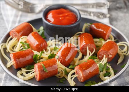 Wiener e Noodle Spider snack con ketchup da vicino in un piatto sul tavolo. Orizzontale Foto Stock