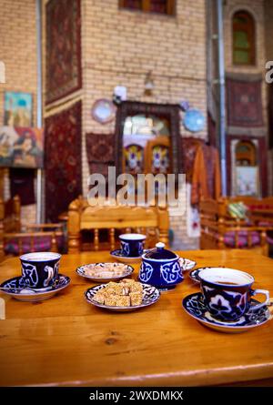 Tradizionale tavolo da tè uzbeko con tazze e dolci orientali nella caffetteria di Bukhara in Uzbekistan, Asia centrale Foto Stock