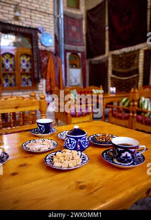 Tradizionale tavolo da tè uzbeko con tazze e dolci orientali nella caffetteria di Bukhara in Uzbekistan, Asia centrale Foto Stock