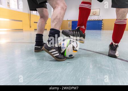 Fußball in Deutschland Göttingen, Deutschland - 26. März 2024: Zwei Senioren tragen Fußballschuhe der Marke adidas und spielen Fußball mit einem offiziellen Spielball für die Euro 2024 in Deutschland mit dem Aufdruck adidas EURO24 Fußballliebe Pro. Niedersachsen Foto Stock