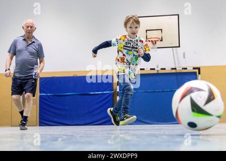 Fußball in Deutschland Göttingen, Deutschland - 26. März 2024: Ein sieben Jahre alter Junge spielt mit seinem 82 Jahre alten Großvater Fußball mit einem offiziellen Spielball für die Euro 2024 in Deutschland mit dem Aufdruck adidas EURO24 Fußballliebe Pro. Niedersachsen Foto Stock