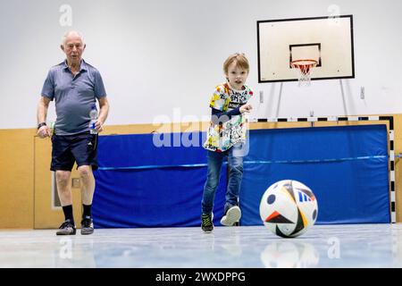 Fußball in Deutschland Göttingen, Deutschland - 26. März 2024: Ein sieben Jahre alter Junge spielt mit seinem 82 Jahre alten Großvater Fußball mit einem offiziellen Spielball für die Euro 2024 in Deutschland mit dem Aufdruck adidas EURO24 Fußballliebe Pro. Niedersachsen Foto Stock