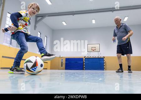 Fußball in Deutschland Göttingen, Deutschland - 26. März 2024: Ein sieben Jahre alter Junge spielt mit seinem 82 Jahre alten Großvater Fußball mit einem offiziellen Spielball für die Euro 2024 in Deutschland mit dem Aufdruck adidas EURO24 Fußballliebe Pro. Niedersachsen Foto Stock