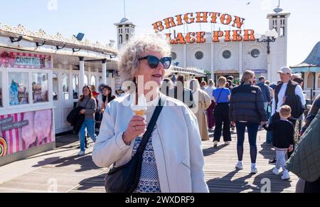 Brighton Regno Unito 30 marzo 2024 - tempo per un gelato sul molo mentre i visitatori godono di una bella e calda giornata di sole sul lungomare di Brighton con più previsioni di sole per la domenica di Pasqua di domani : Credit Simon Dack / Alamy Live News Foto Stock