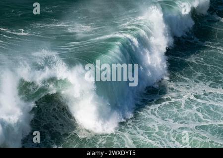 Onde oceaniche turchesi giganti si schiantano sulla superficie dell'acqua formando un arcobaleno Foto Stock