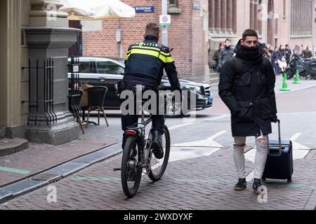 Un poliziotto in bicicletta pattuglia le strade della città, passa tra i turisti, controlla il rispetto della legge e dell'ordine. Paesi Bassi, Amsterdam, gennaio 2020. Foto Stock