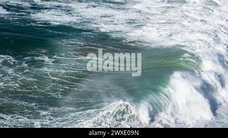 Onde oceaniche turchesi giganti si schiantano sulla superficie dell'acqua formando un arcobaleno Foto Stock