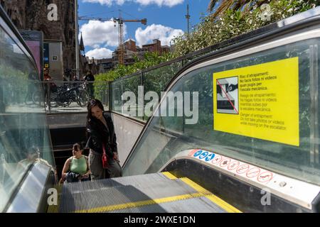 Le scale meccaniche di uscita della stazione della metropolitana Sagrada Familia di Barcellona sono diventate virali, al punto che l'autorità di trasporto di Barcellona ha dovuto apporre dei cartelli segnaletici sul divieto di posizionare telefoni sulle scale mobili. Hanno anche posto una guardia di sicurezza nelle vicinanze per far rispettare il divieto, anche se i turisti non lo prestano molta attenzione. Las escaleras mecánicas de salida del metro de la parada de Sagrada Familia, en Barcelona, se han vuelto virales, hasta el punto de que la autoridad del transporte de Barcelona ha tenido que colocar carteles que advierten sobre la hibi Foto Stock