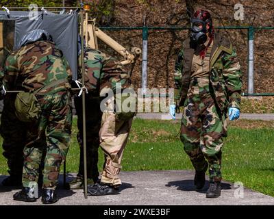 Un gruppo di soldati in uniformi mimetiche stanno lavorando insieme. Uno di loro indossa una maschera antigas Foto Stock