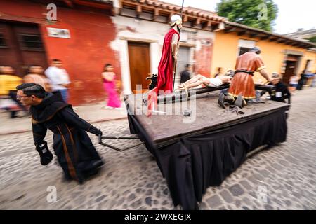 Antigua, Guatemala. 29 marzo 2024. I penitenti cattolici lanciano un galleggiante processionale, parte di una serie di momenti finali di Cristo mentre si preparano per la processione del Santo venerdì del Senor Sepultado Escuela de Cristo durante la Semana Santa, 29 marzo 2024 ad Antigua, Guatemala. L'opulenta processione è una delle più grandi al mondo. Crediti: Richard Ellis/Richard Ellis/Alamy Live News Foto Stock