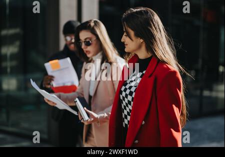 Giovani compagni di squadra professionisti che camminano all'aperto con documenti. Foto Stock