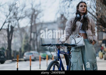 Ciclista urbano che si prende una pausa, godendosi l'atmosfera della città con le cuffie. Foto Stock