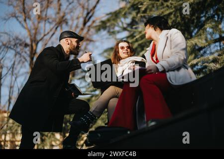 Un gruppo di giovani imprenditori in un ambiente urbano all'aperto discutono le strategie per la crescita del business, le tendenze del mercato e il successo. Foto Stock