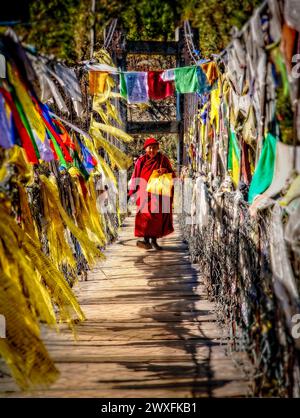 Un monaco attraversa il ponte sospeso sul Chamkhar Chhu (fiume) che scorre attraverso Jakar in Bhutan. Foto Stock
