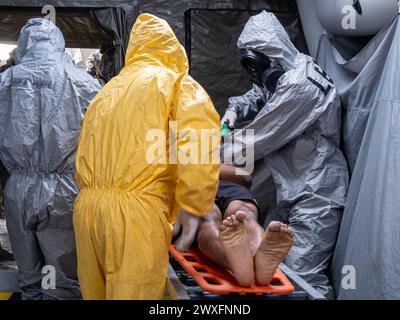 Un uomo in tuta gialla sta aiutando un uomo su una barella Foto Stock