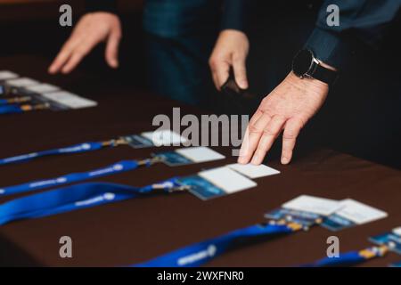 Processo di check-in su un evento del forum congressuale, tavolo di registrazione, visitatori e partecipanti che ricevono un badge con il nome e un polso d'ingresso Foto Stock