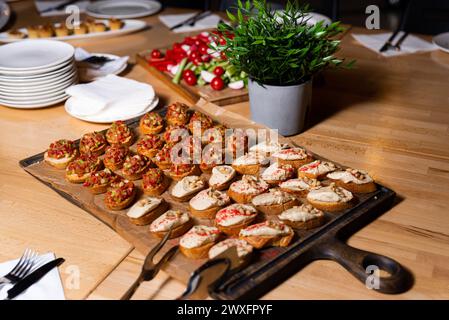 Una selezione di condimenti di bruschette, tra cui pomodoro e basilico, e formaggio spalmabile con noci, serviti su fette tostate su una tavola di legno. Foto Stock