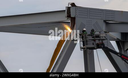 Gli equipaggi di demolizione altamente addestrati iniziarono a tagliare la parte superiore del lato nord del ponte crollato in sezioni più piccole per la rimozione sicura tramite gru nel fiume Patapsco, a Baltimora, Maryland, 30 marzo 2024. Le squadre di recupero utilizzano una torcia da taglio esotermica per separare sistematicamente sezioni del ponte in acciaio, che verrà portata in un sito di smaltimento. (Foto della Guardia Costiera degli Stati Uniti del sottufficiale di terza classe Kimberly Reaves) Foto Stock