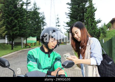Taxi donna Motrobike cliente che ordina il trasporto online o Ojek Online Foto Stock