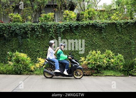 Moto taxi on-line con passeggeri femminili. Moto taxi Gojek, trasporto popolare in Indonesia Foto Stock