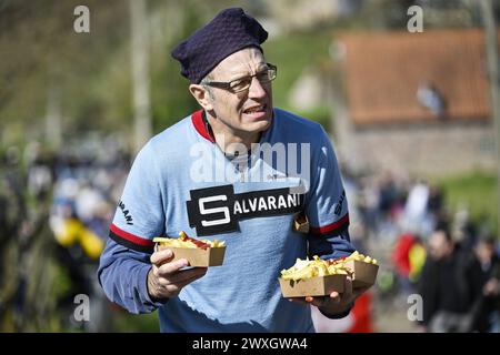 Kluisbergen, Belgio. 31 marzo 2024. L'immagine mostra un appassionato di ciclismo che tiene patatine fritte al Paterberg durante la gara maschile del 'Ronde van Vlaanderen/ Tour des Flandres/ Tour of Flanders', 270 km da Anversa a Oudenaarde, domenica 31 marzo 2024. BELGA PHOTO TOM GOYVAERTS credito: Belga News Agency/Alamy Live News Foto Stock