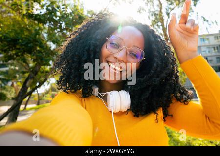Vista frontale di una allegra donna nera con un sorriso che fa una videochiamata al telefono. Foto Stock