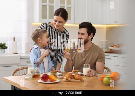 La famiglia felice con la colazione a tavola in cucina Foto Stock