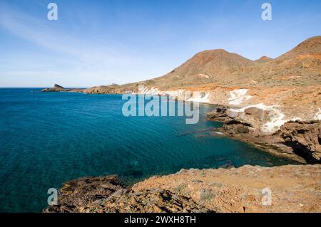 Tranquillo mare blu con scogliere vicino all'acqua e sullo sfondo delle montagne Foto Stock