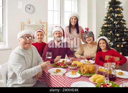 Foto di gruppo di una famiglia multigenerazione sui cappelli di babbo natale che si diverte alla festa di natale. Foto Stock