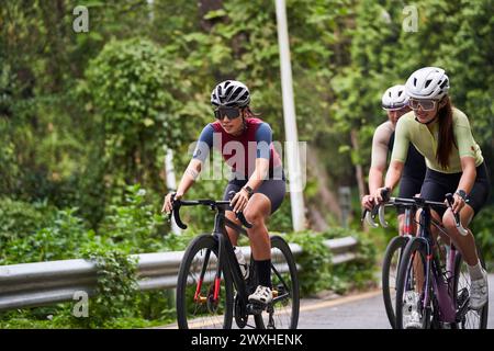 gruppo di tre giovani ciclisti adulti asiatici che cavalcano in bicicletta all'aperto su strada rurale Foto Stock