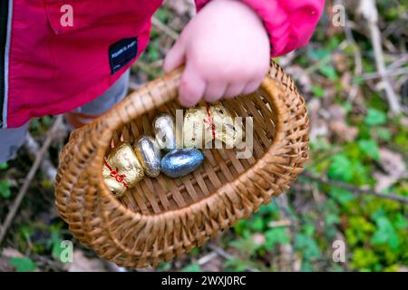 Caccia all'uovo di Pasqua bambini con cesto di uova di Pasqua al Carmarthenshire Galles March Garden 2024 Regno Unito Gran Bretagna KATHY DEWITT Foto Stock