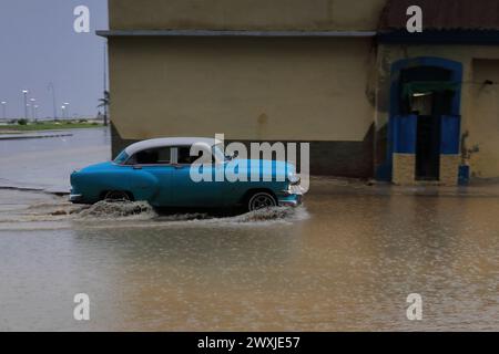 127 auto in alluminio blu, classica Chevrolet del 1954, guida fino a Marina Street gustando una profonda pozzanghera sotto la forte pioggia di una tempesta tropicale. L'Avana-Cuba. Foto Stock