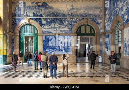 I visitatori ammirano il murale in piastrelle azulejo presso la stazione ferroviaria di Sao Bento, Porto, Portogallo Foto Stock