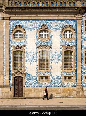 La donna passa davanti alla facciata della chiesa di Igreja do Carmo, adornata con intricate piastrelle blu e bianche, Porto, Portogallo Foto Stock